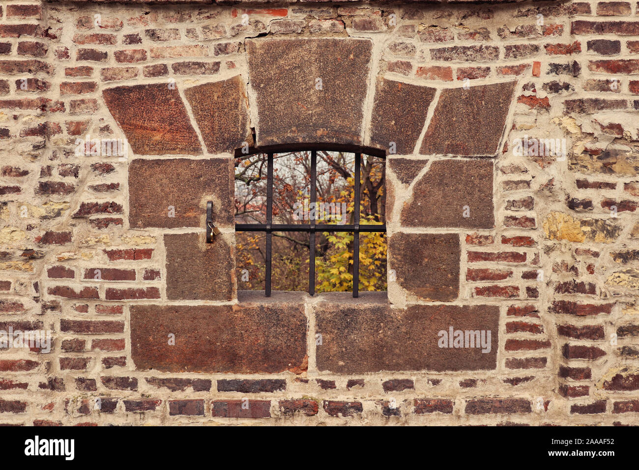 Dettaglio di apertura / scappatoia in montagna con ferro forgiato reticolo incorniciato con blocchi di pietra in un vecchio mattone / muratura mura di fortificazione del Castello di Vyšehrad, Praga Foto Stock