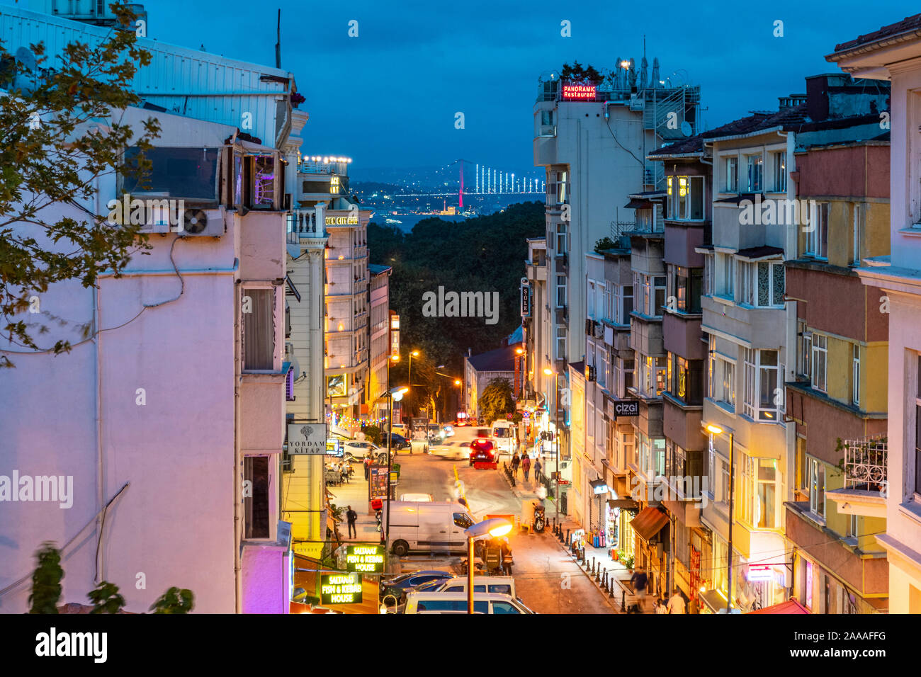 Vista notturna da una finestra di livello superiore che si affaccia su una strada trafficata a Istanbul, Turchia, con il Ponte del Bosforo e la Moschea di Ortaköy illuminati. Foto Stock