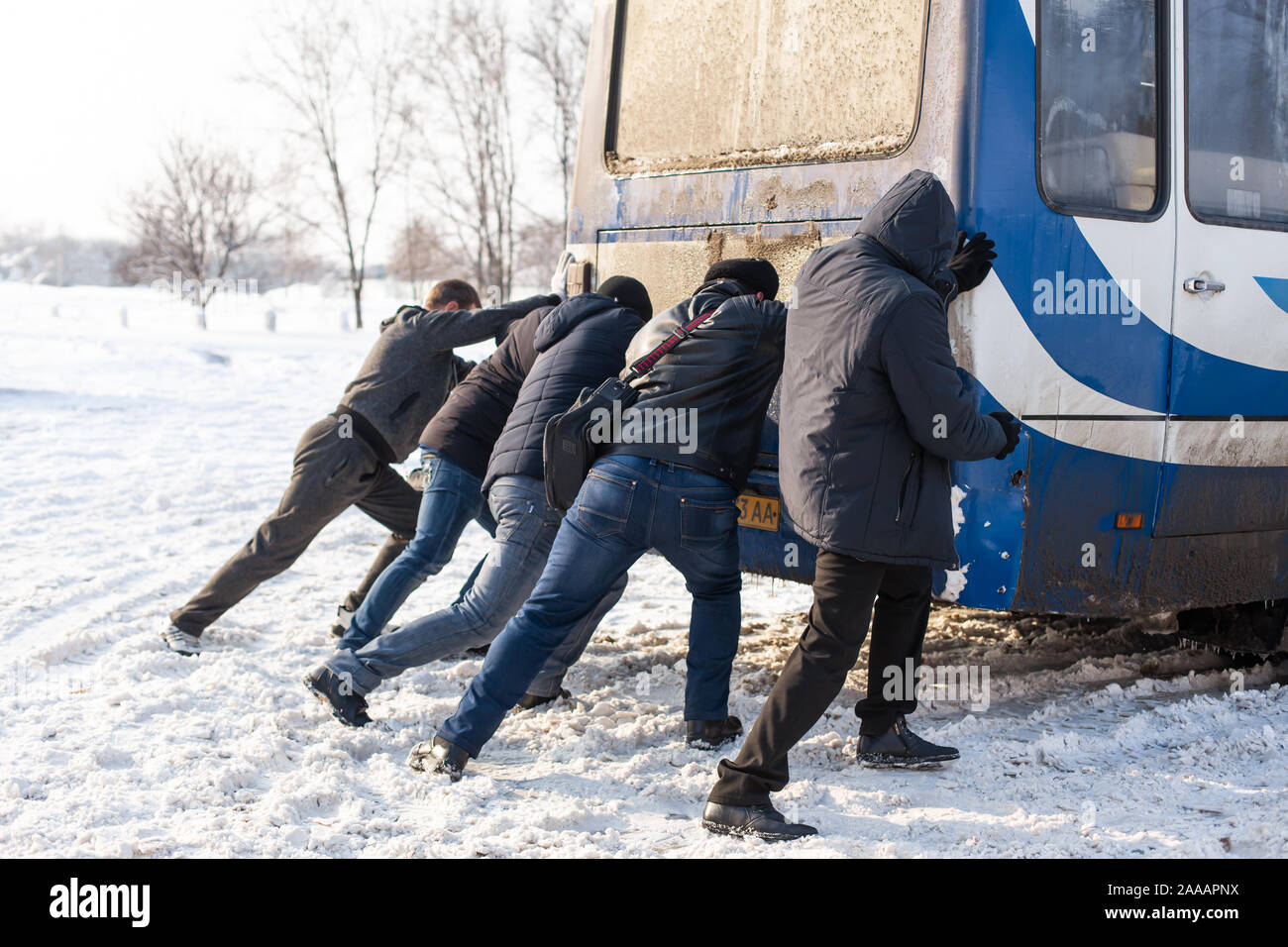 Una folla di persone che stanno spingendo per un autobus che è rimasto bloccato nella neve. Le condizioni meteorologiche sfavorevoli. La neve che paralizza il traffico. Foto Stock