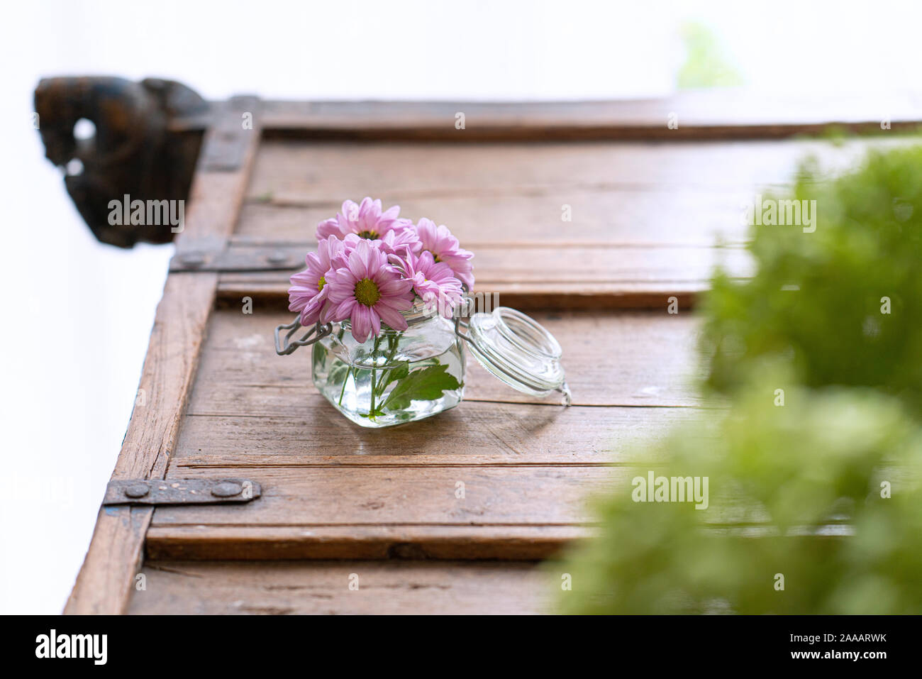 Fiori d'estate in un piccolo vaso di vetro dal di sopra su un rustico armadio in legno, unsharp fiori in primo piano Foto Stock