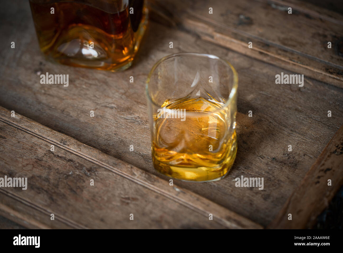 Close up d'oro scintillanti whisky in un bicchiere e bottiglia su un vecchio trasandato botte di rovere Foto Stock