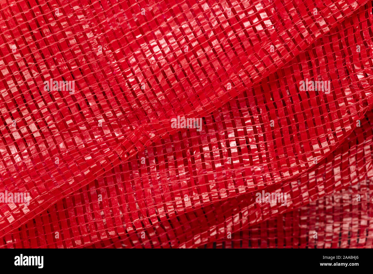 Tessuto rosso rete in plastica per il confezionamento di frutta e verdura, prodotti o. Abstract close-up dello sfondo. Il polietilene espanso texture. Foto Stock