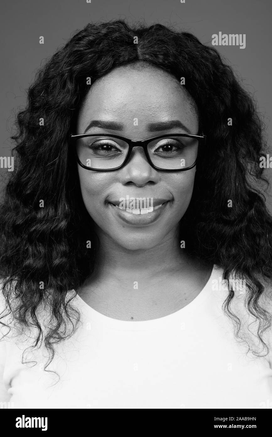 Giovane bella donna africana indossando occhiali contro uno sfondo grigio Foto Stock