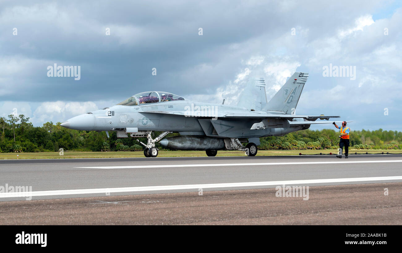 Un U.S. Air Force pompiere segnali pilota di U.S. Navy Strike Fighter Squadron 106 F/A-18F Super Hornet aeromobile dopo un arrestato in atterraggio a MacDill Air Force Base Fla., Ott 16, 2019. Arrestati gli sbarchi di consentire ai piloti di ottenere una rapida decelerazione quando lo sbarco a bordo degli aeromobili del vettore collegando un tailhook ad un cavo, che assorbe l'energia del velivolo. (U.S. Air Force foto di Senior Airman Caleb Nunez) Foto Stock