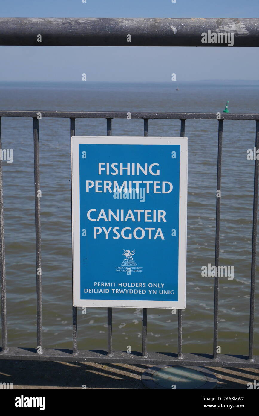 Cartello bilingue sulle ringhiere in inglese e gallese dicendo pesca consentita e non la pesca, Cardiff Bay Barrage, Cardiff Wales, Regno Unito Foto Stock