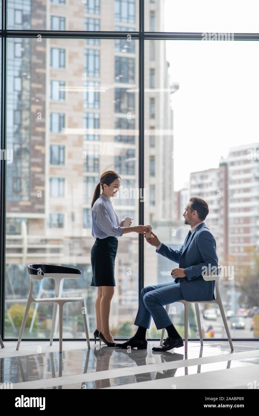 Segretario utile portare il caffè al mattino al suo boss al mattino Foto Stock
