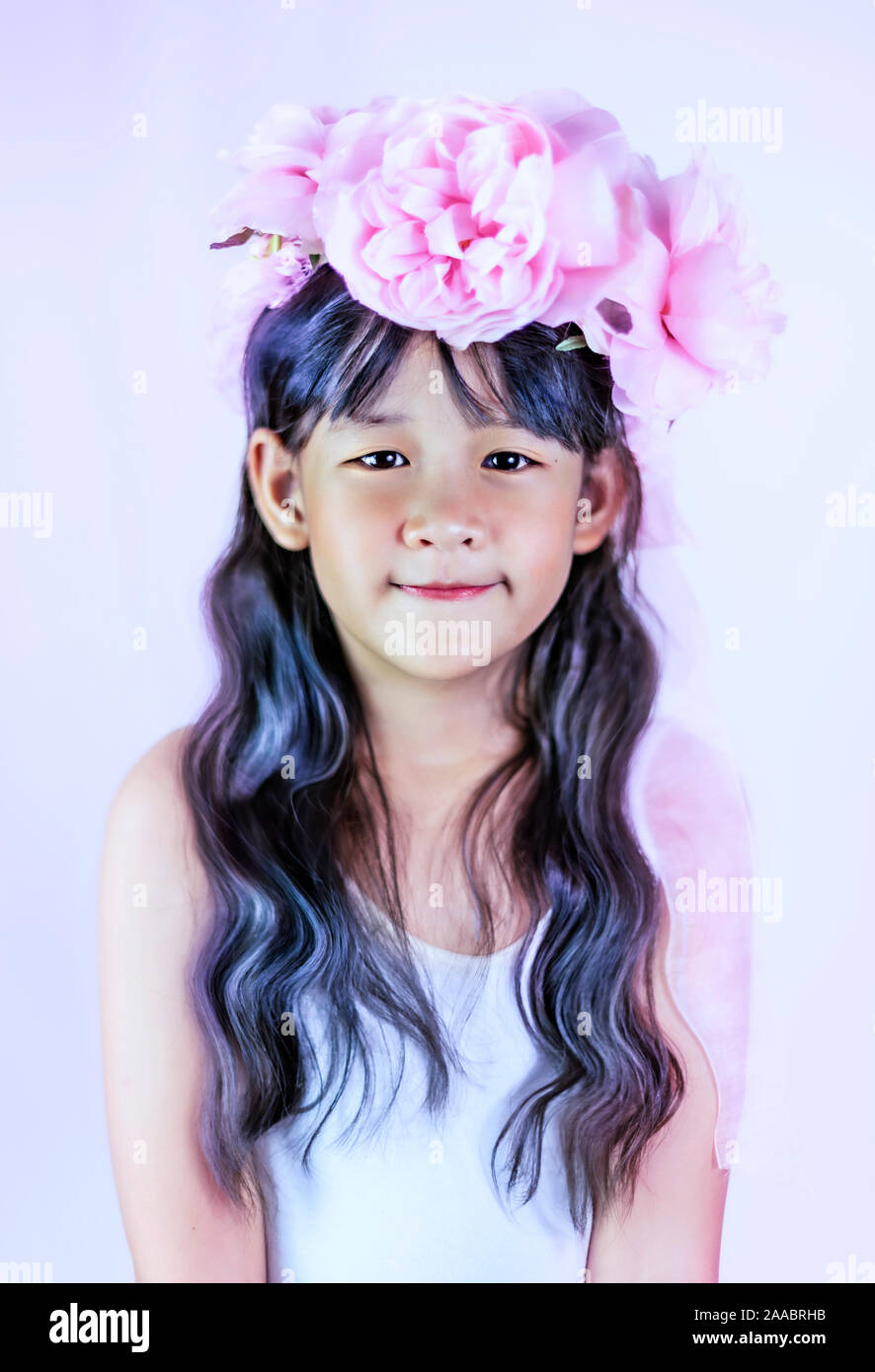 Asian piccola ragazza con i capelli neri vestito con una ghirlanda di fiori sulla sua testa Foto Stock