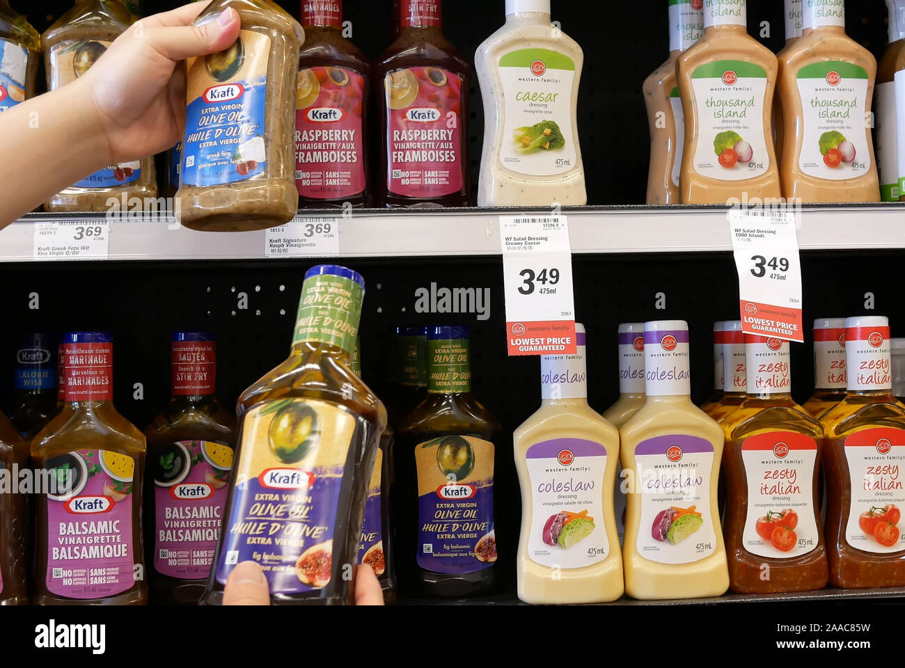 Burnaby, BC, Canada - 09 Maggio 2019 : il movimento di persone confrontando due diversi di olio d'oliva all'interno di medicazione price smart foods store Foto Stock