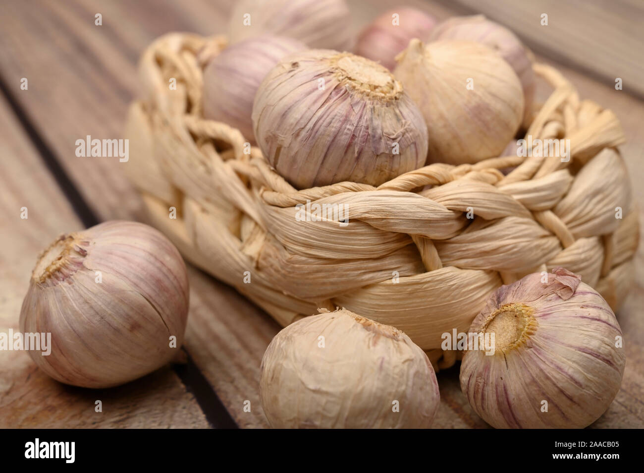 A pochi capi di giovani aglio in un cesto di vimini su un sfondo di legno. Raccolto autunnale. L'agricoltura moderna. Close up Foto Stock