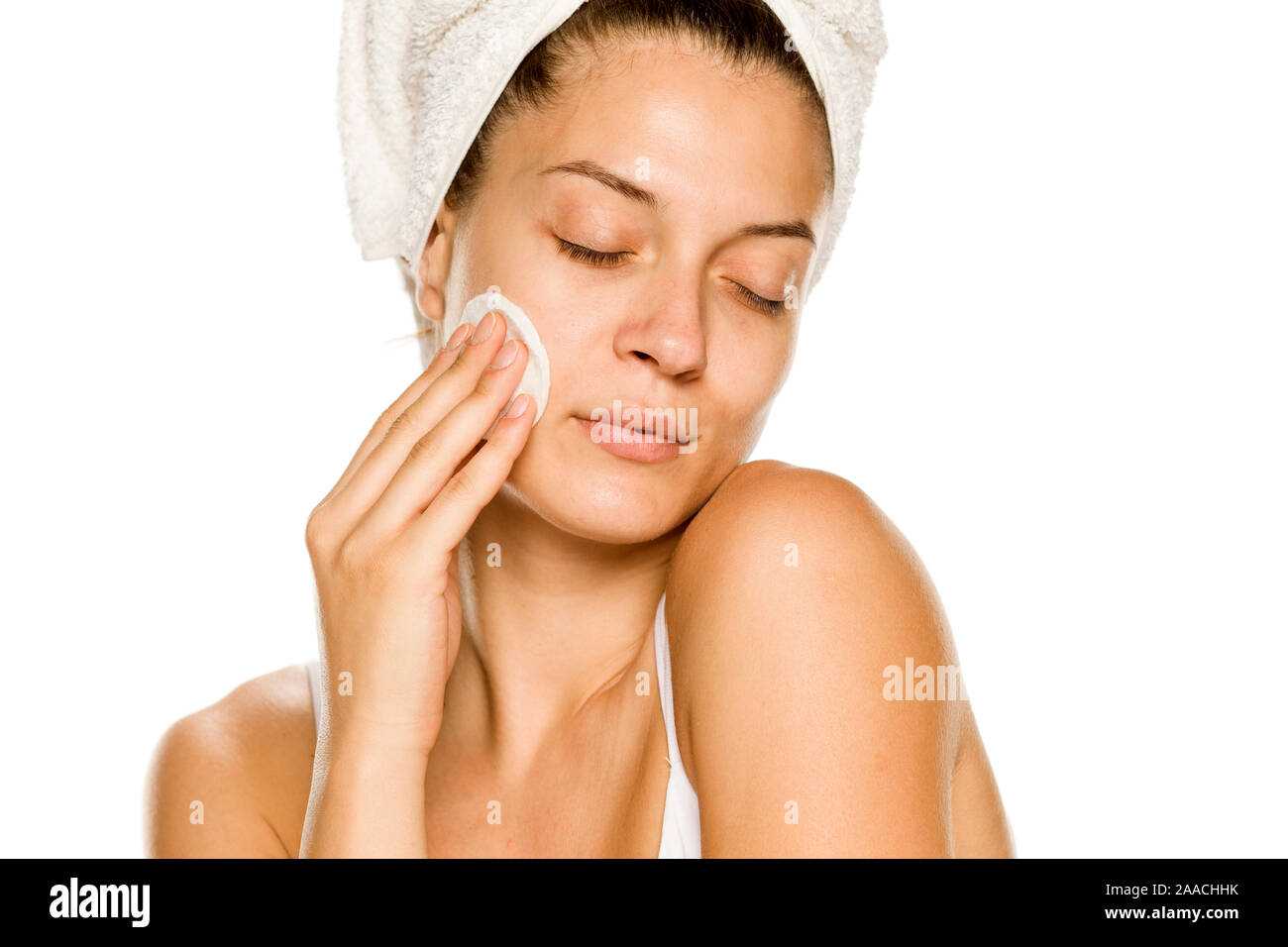 Giovane donna bella claning il suo volto con tamponi di cotone su sfondo bianco Foto Stock