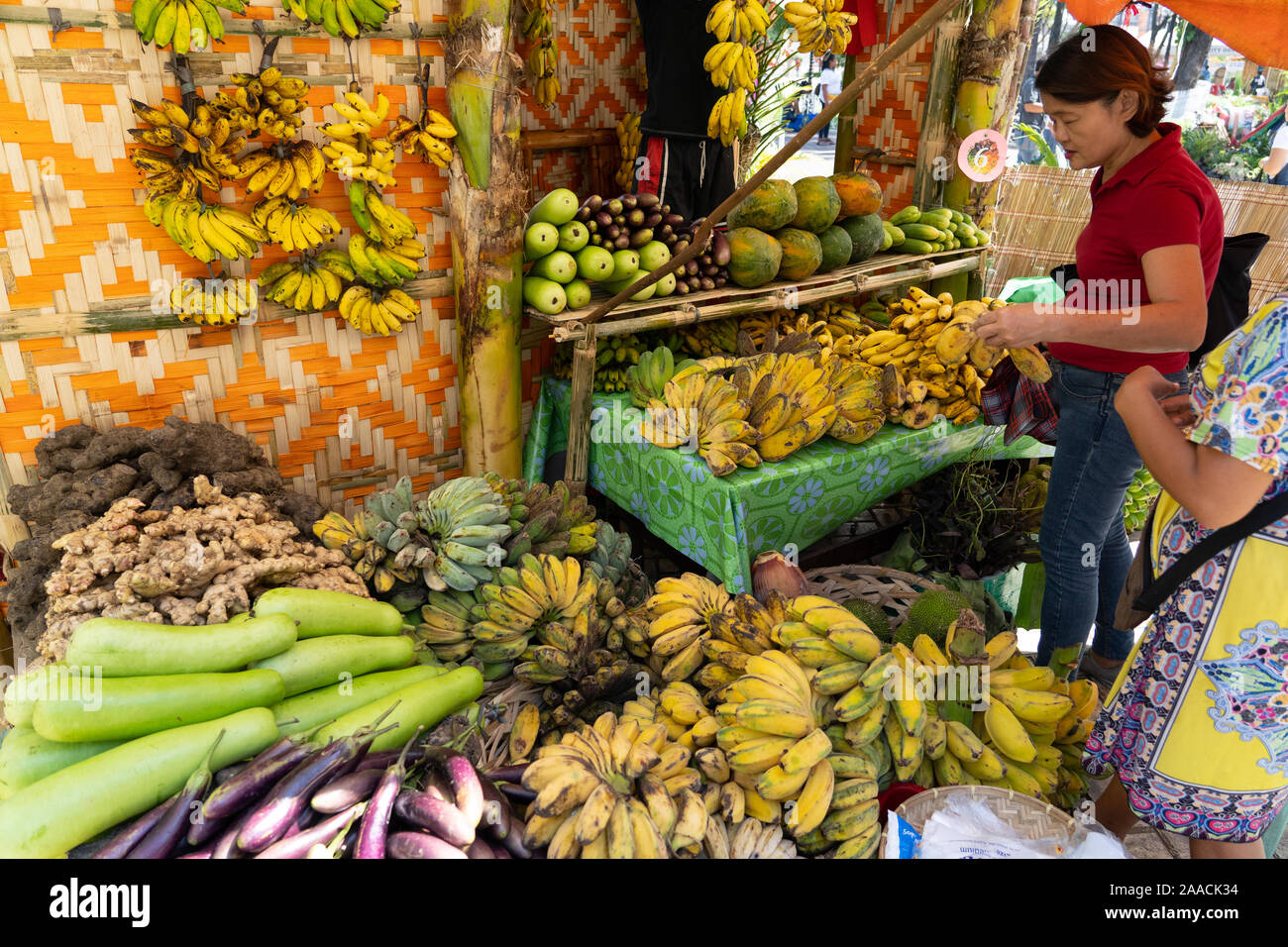 Una donna scelta di frutta da una frutta & verdura in stallo entro un mercato degli agricoltori,Cebu City, Filippine Foto Stock