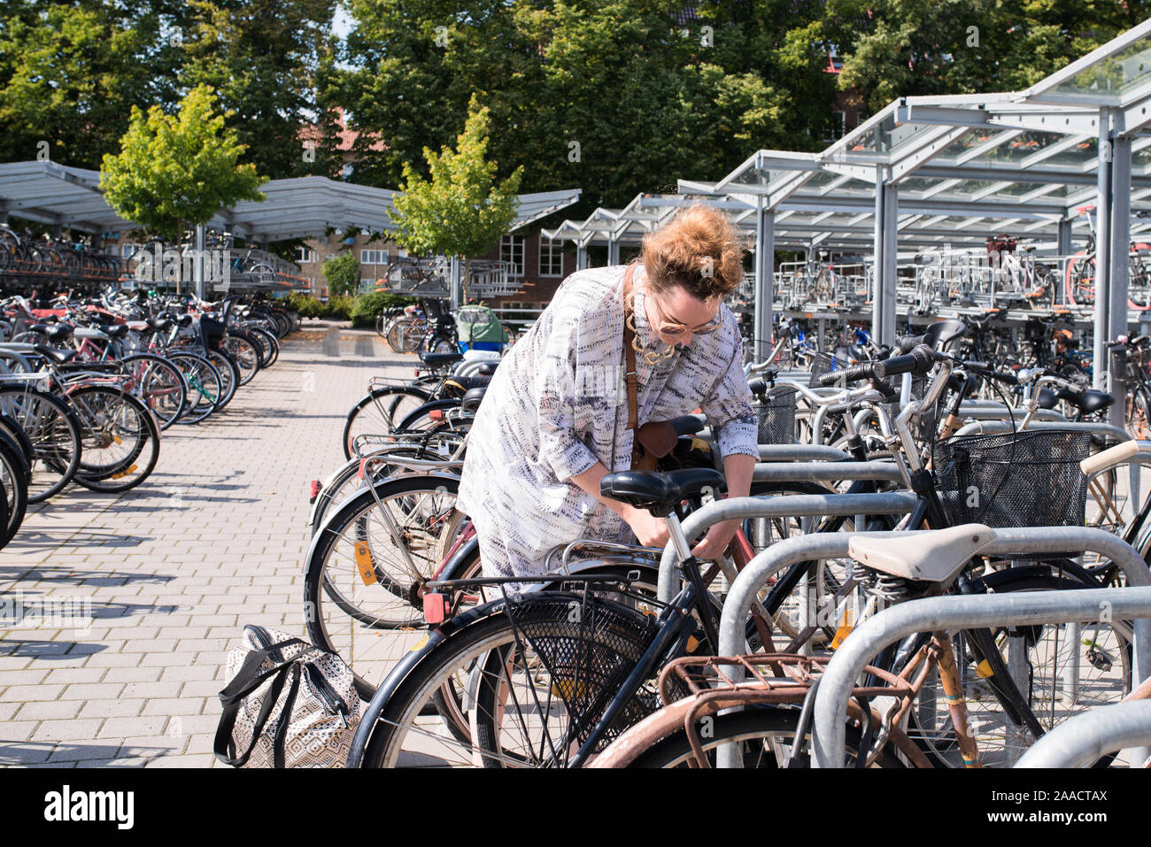 Anca donna lo sblocco il suo moto dalla bicicletta stand in estate Foto Stock