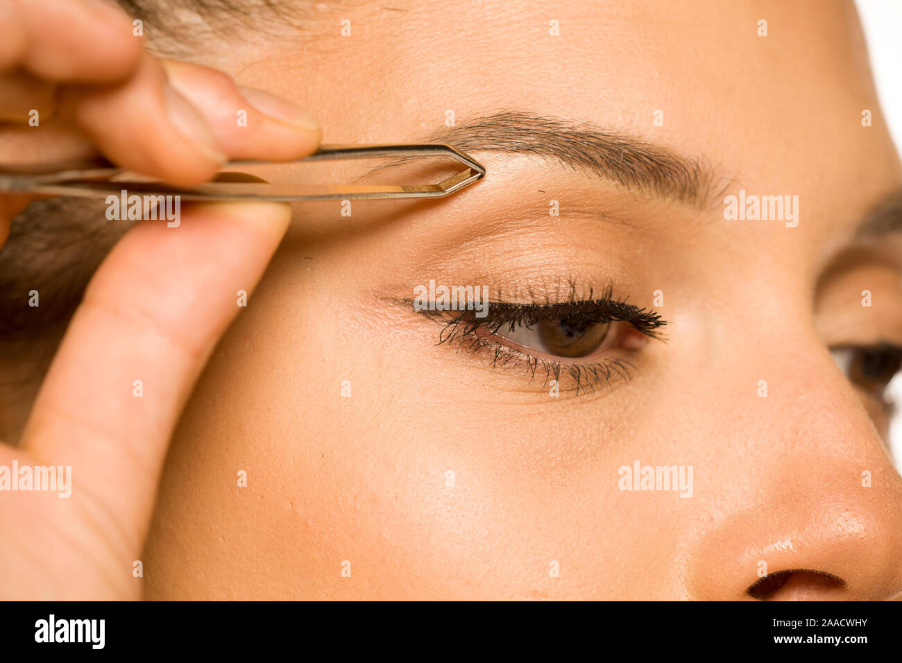 Primo piano della donna spennatura le sopraciglia con pinzette Foto Stock