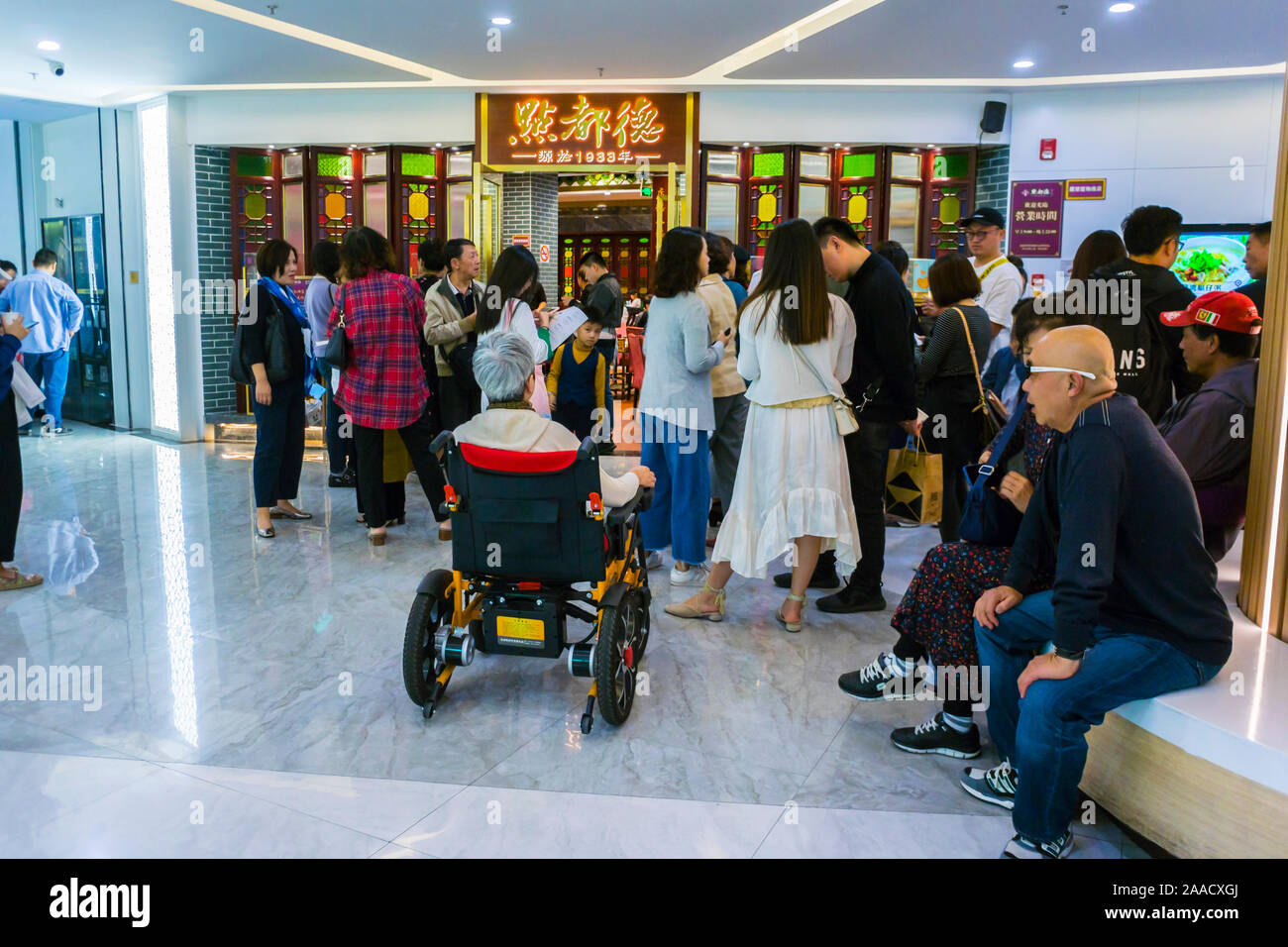 Shanghai, Cina, coda cinese, gente in attesa outisde Hong Kong Ristorante 'dian Du De', in Zhong Hai Huan Yu Hui Shopping Center, Xin Tian di Area, accesso per esigenze speciali Foto Stock