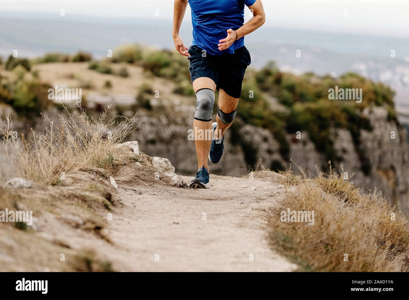 Atleta runner infortunio al ginocchio eseguito in ginocchio i pattini sul sentiero di montagna Foto Stock