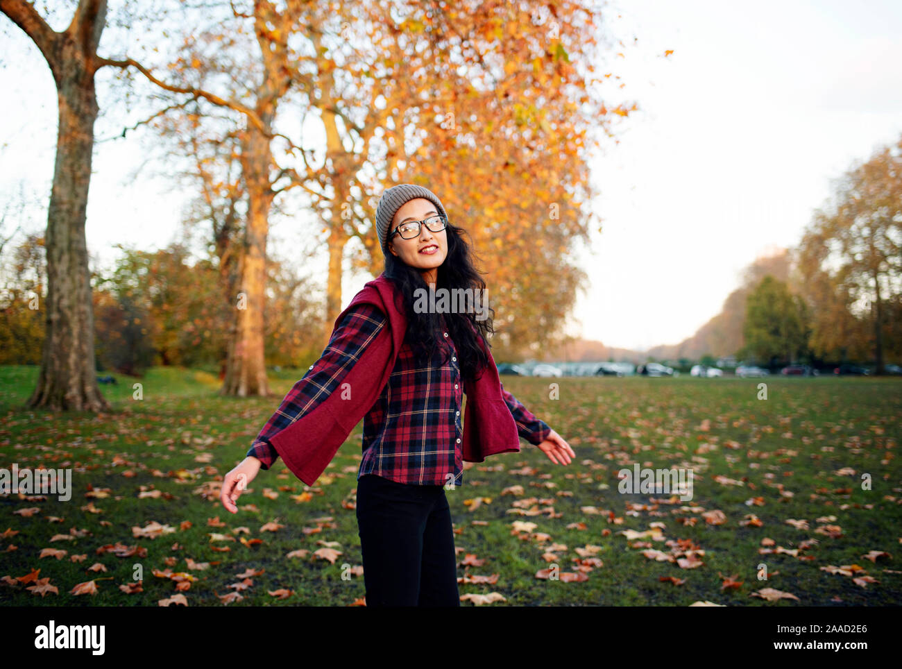 Felice giovane donna asiatica girarsi nel parco. Stile di vita all'aperto RF con colori autunnali. Novembre 2019 Foto Stock