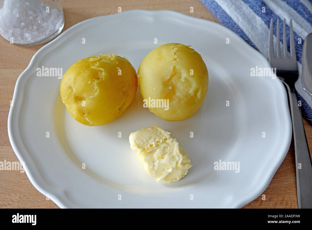 Patate cotte con burro e sale da pranzo o cena sulla piastra bianca. Cose-up Foto Stock
