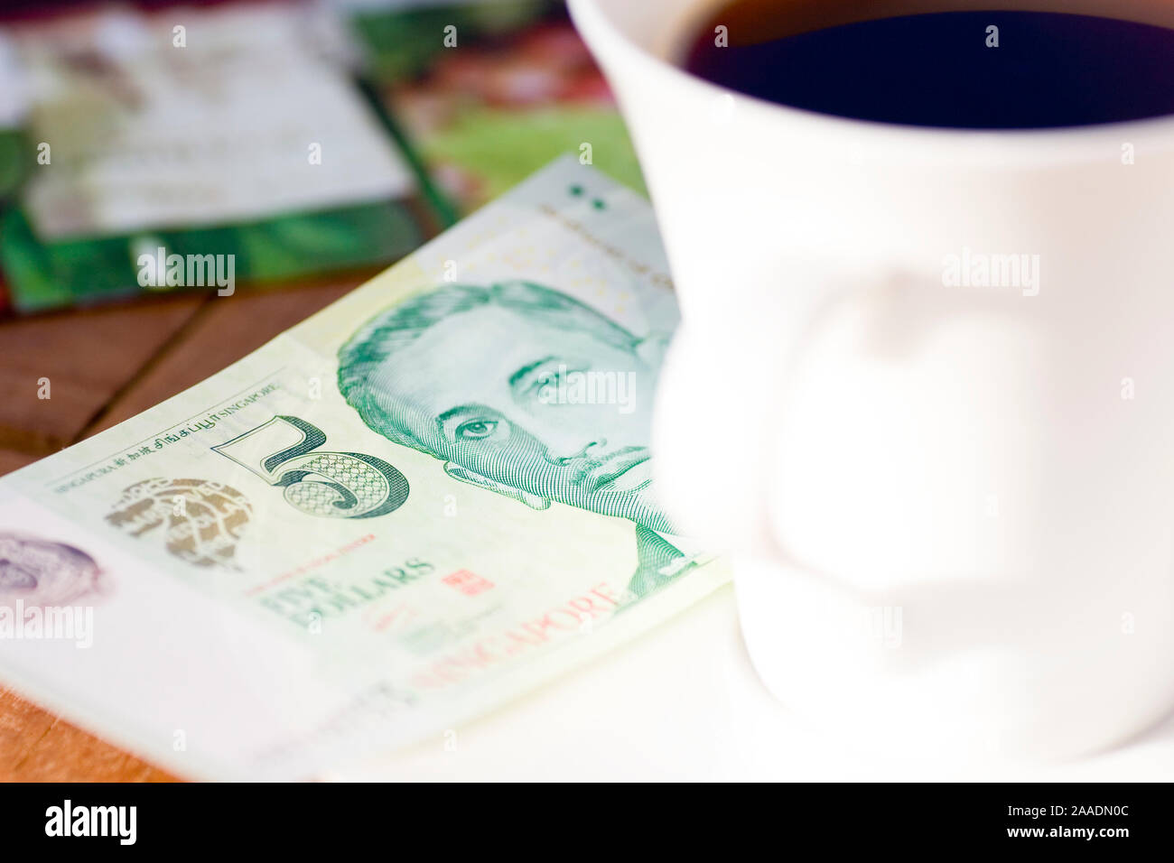 Fünf-Singapur-Dollar Schein neben Kaffeetasse Foto Stock
