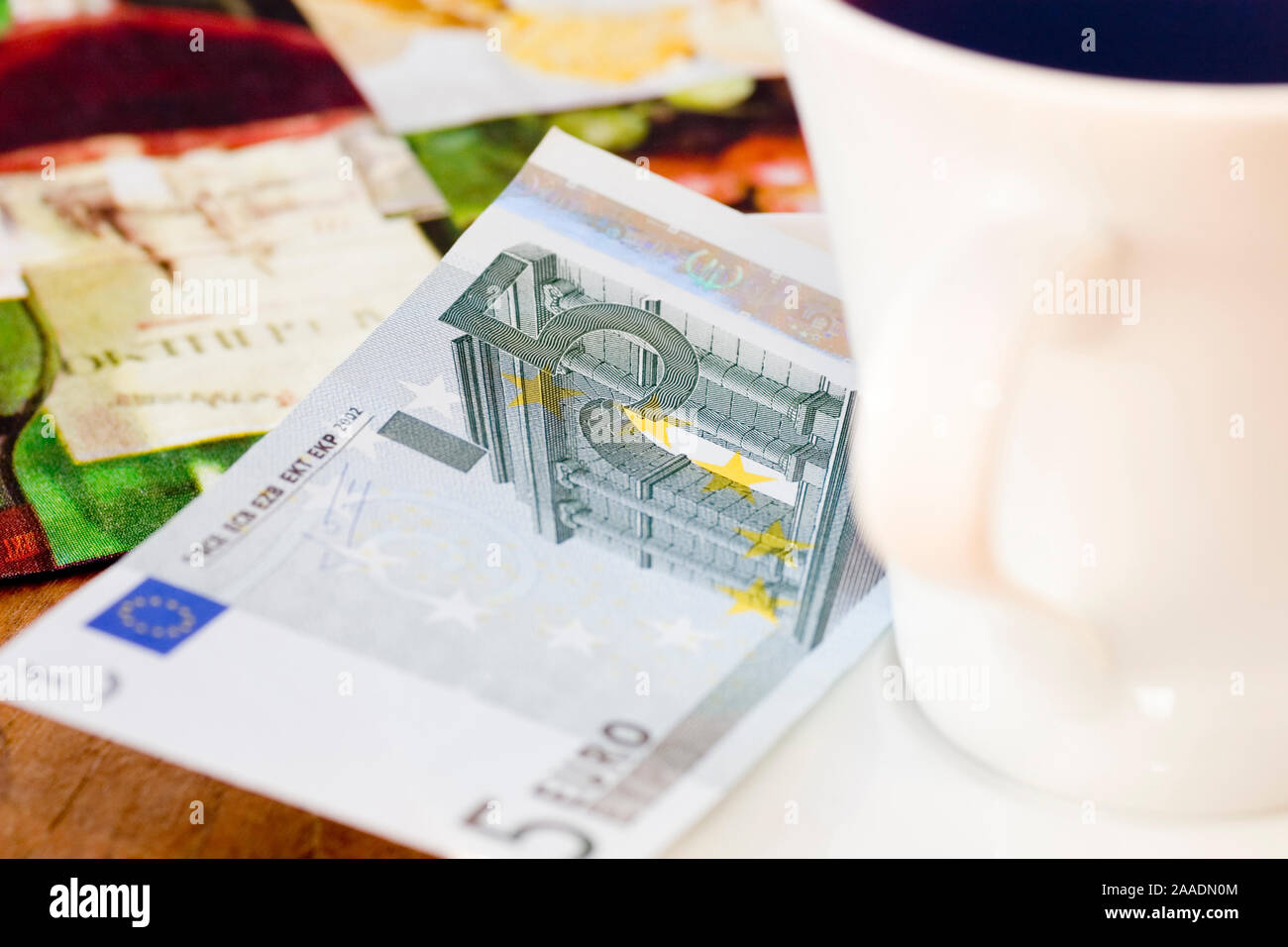 Fünf-Euro-Schein neben Kaffeetasse Foto Stock