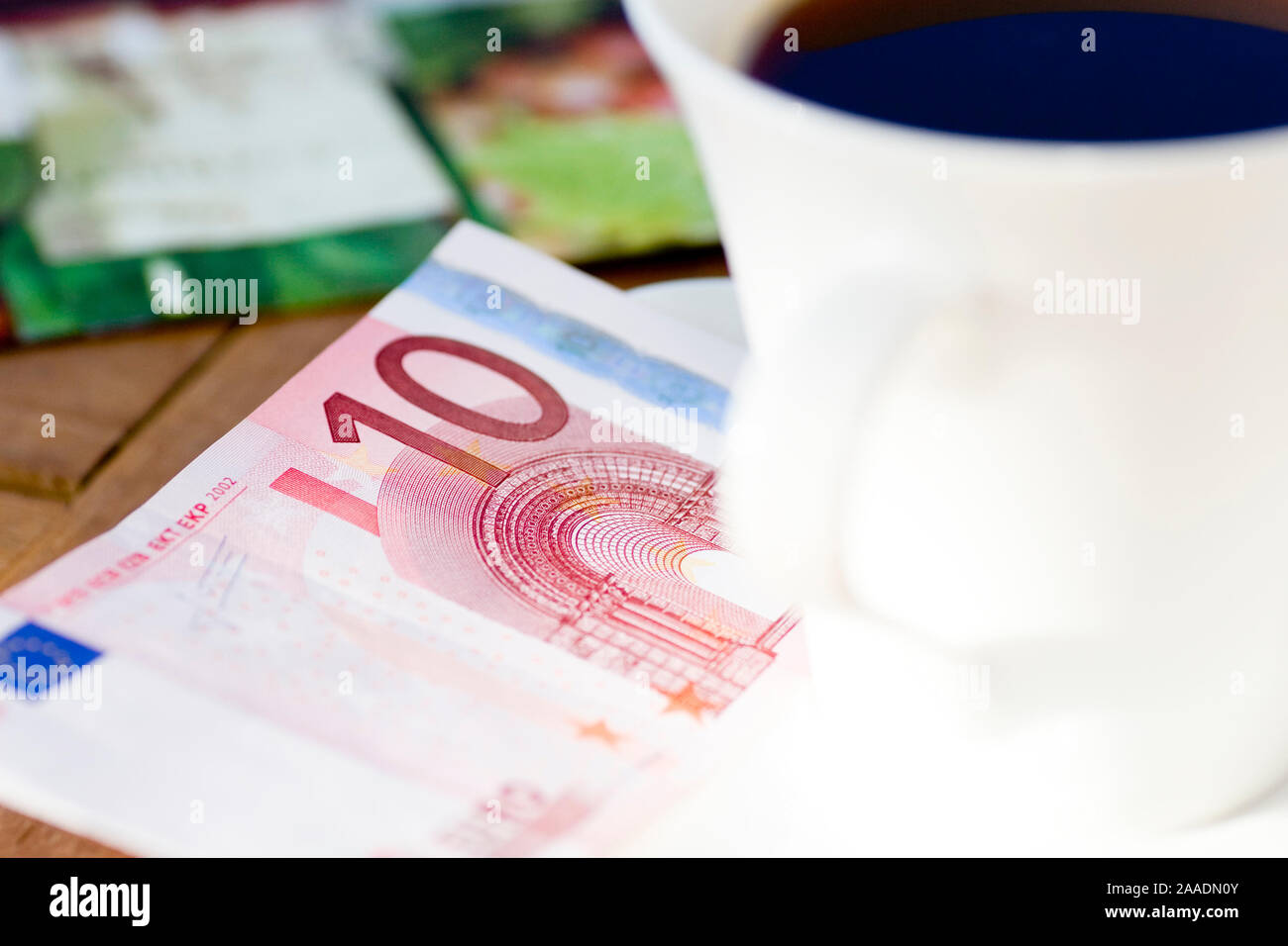 Zehn-Euro-Schein neben Kaffeetasse Foto Stock