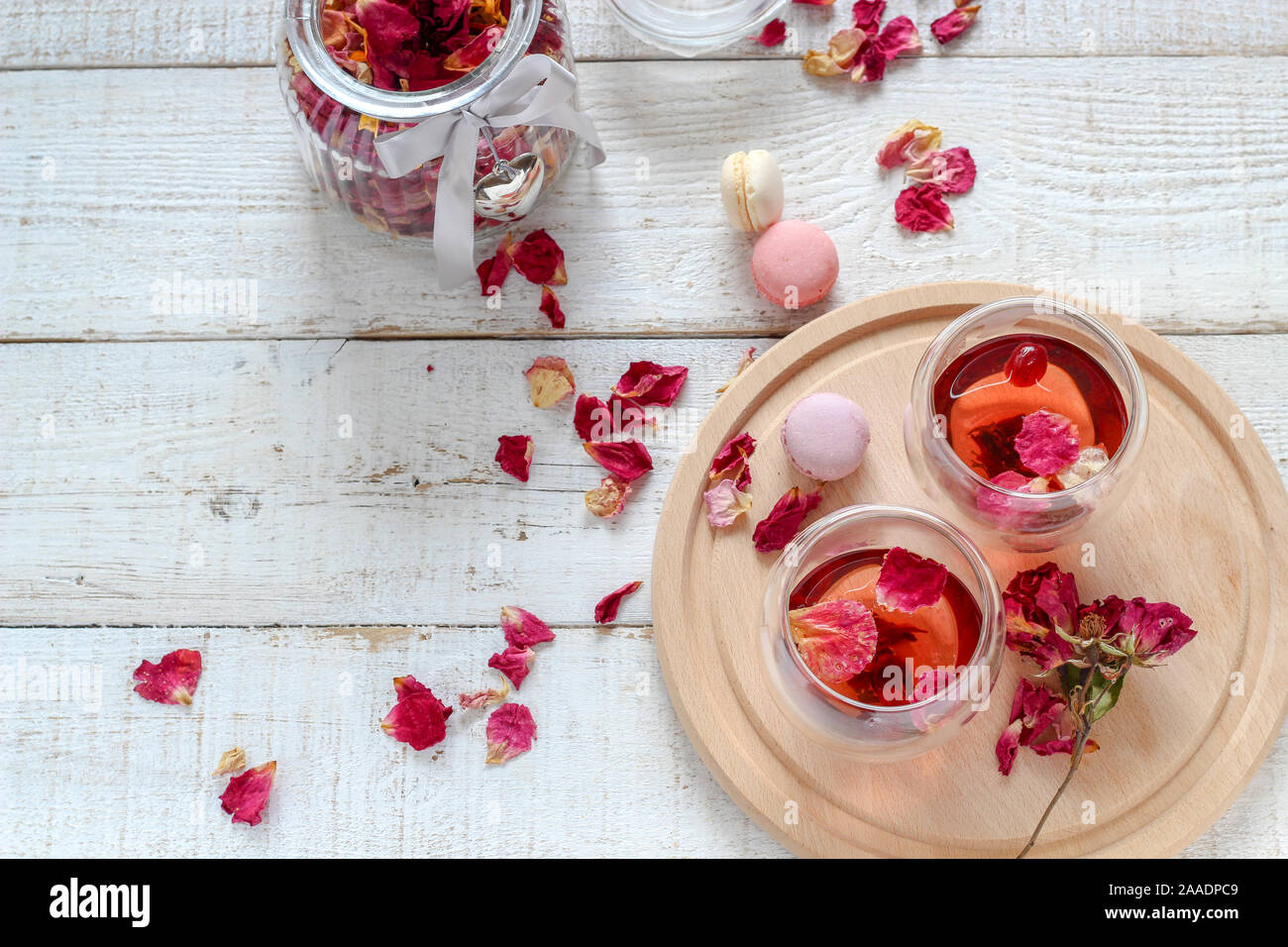 Due tazze di essiccato petali di rosa tea in bianco di un tavolo di legno. Il tè del mattino per due Foto Stock