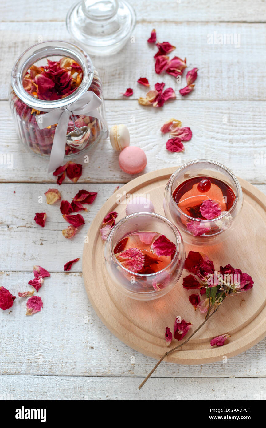 Due tazze di essiccato petali di rosa tea in bianco di un tavolo di legno. Il tè del mattino per due Foto Stock