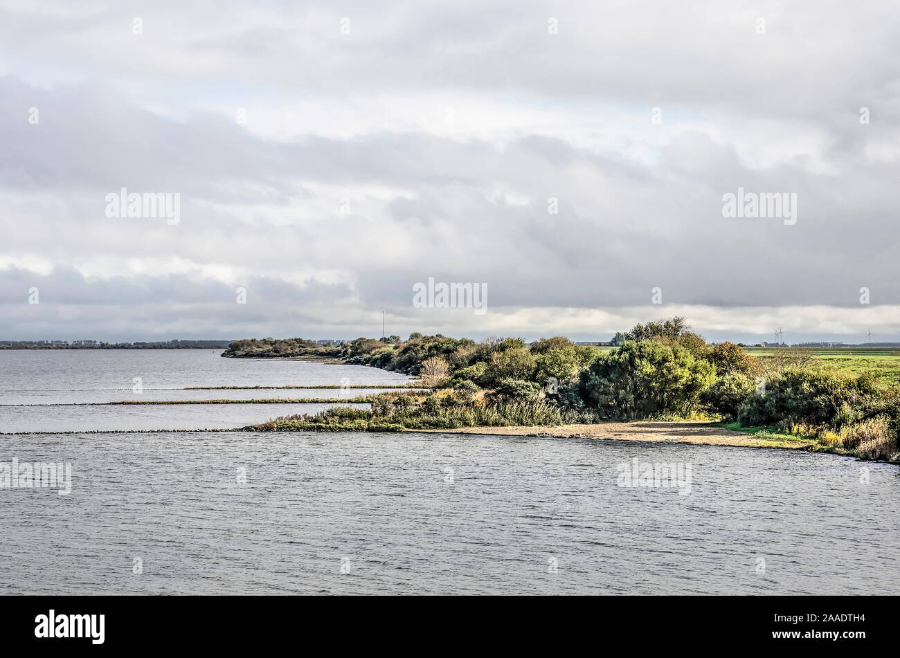 Vista lungo la costa sud di ex estuario, ora sul lago Grevelingen, sull'isola di Schouwen-Duiveland, Paesi Bassi, con scogliere e spiagge di un Foto Stock