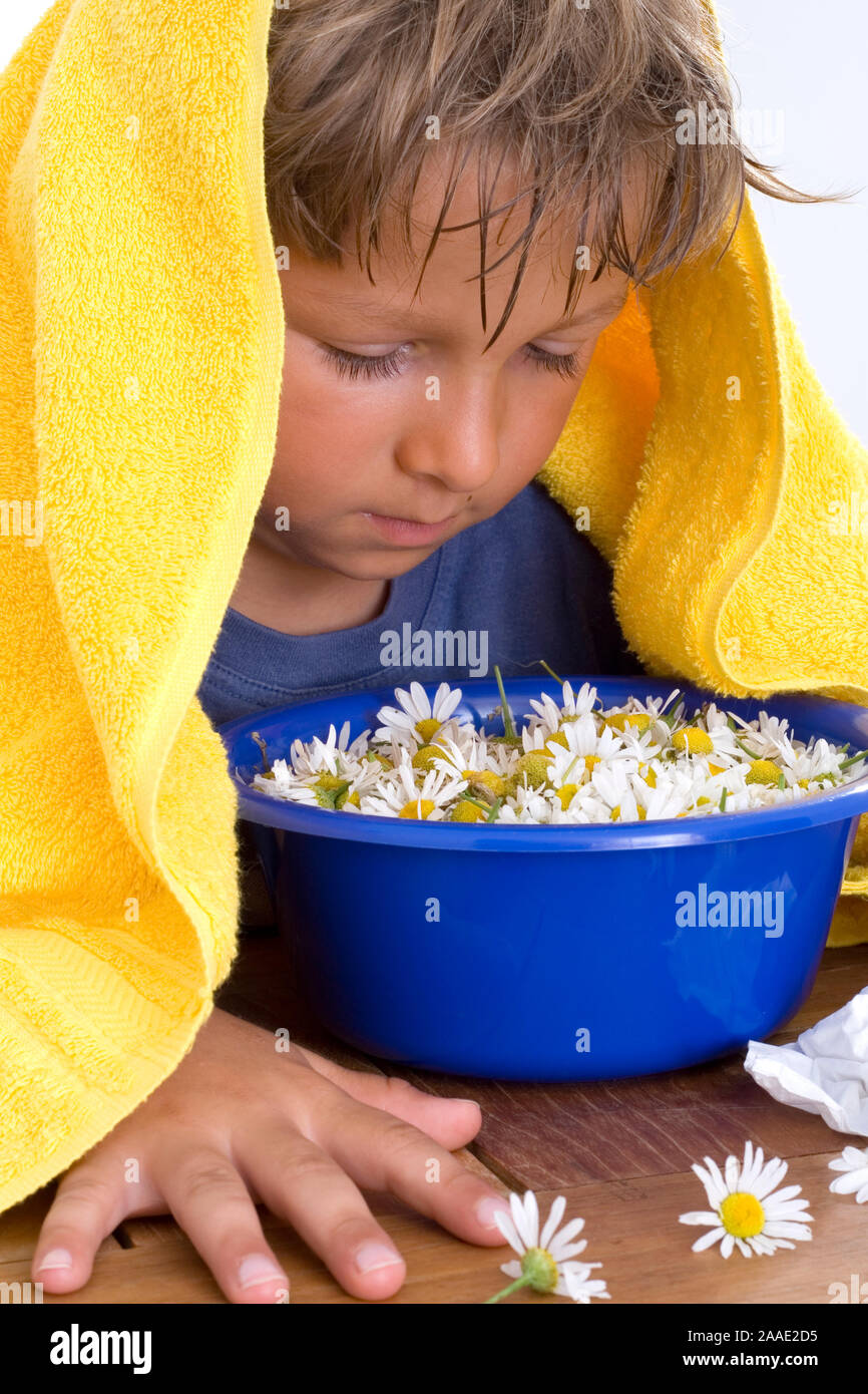 Junge siebenjähriger kuriert Erkältung mit Kamillendampf aus (MR) Foto Stock
