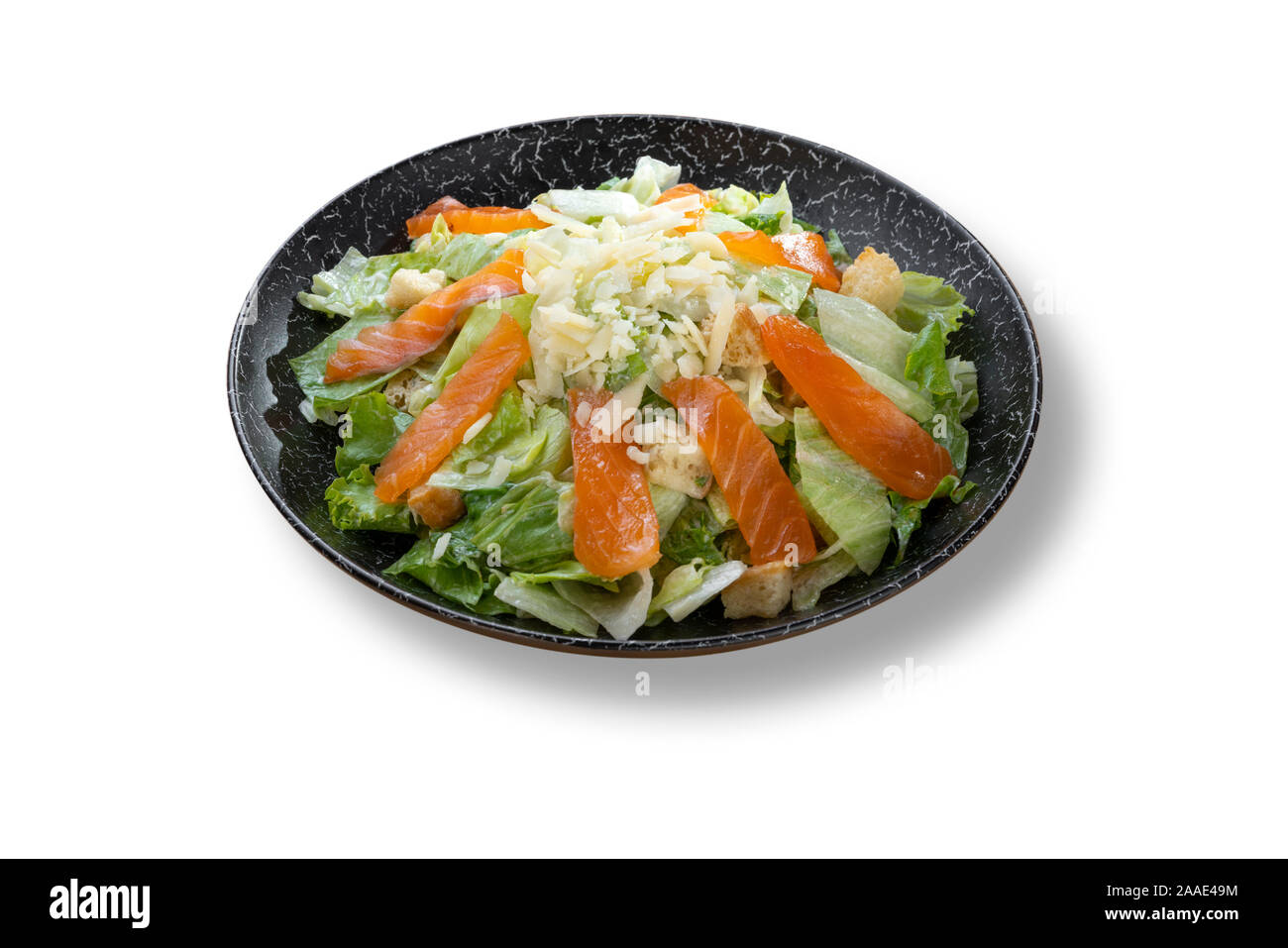 Un'insalata Caesar con salmone e parmigiano nel bellissimo nero piastra moderno Foto Stock