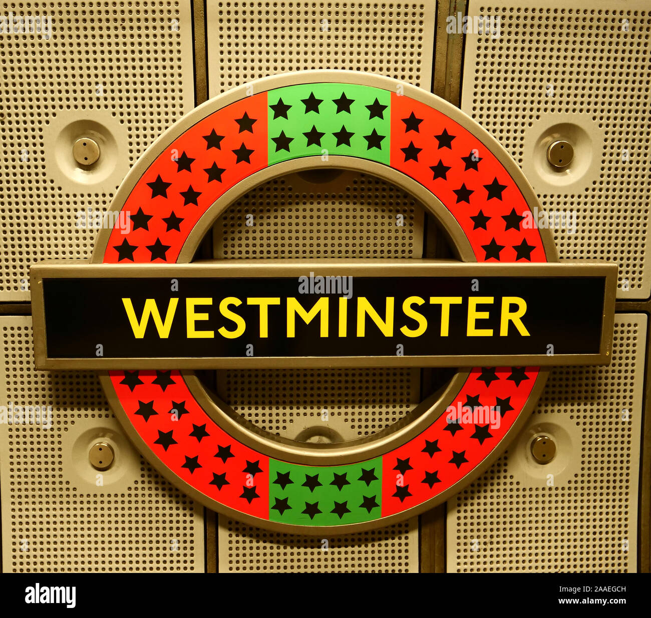 Logo rotondo della metropolitana insolito di Westminster, scritto in giallo su sfondo nero con un cerchio giallo e rosso. Primo piano del cartello su sfondo beige. Foto Stock