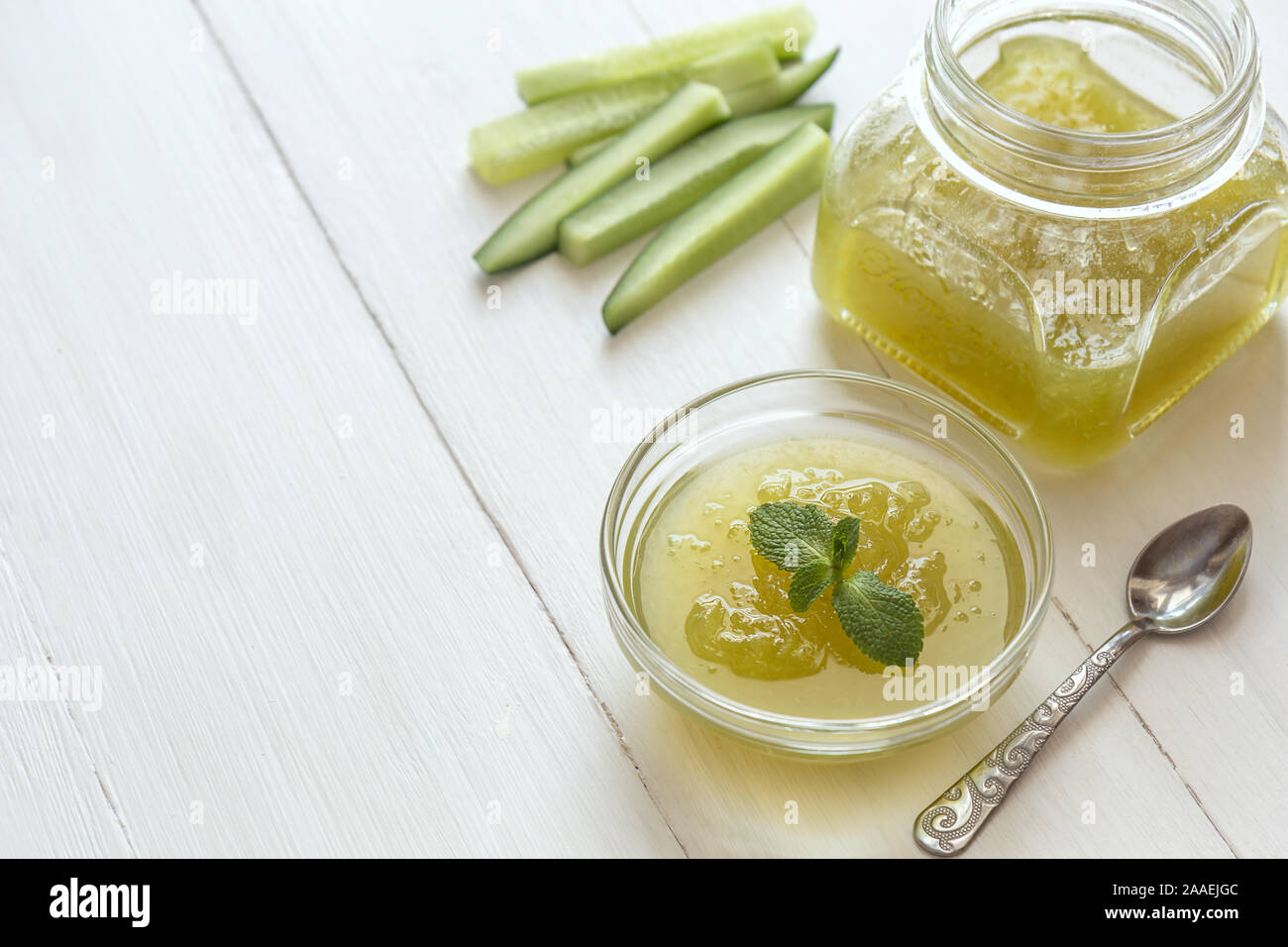 Cetriolo verde inceppamento in un vasetto di vetro e ciotola su un bianco sullo sfondo di legno. Foto orizzontale con posto per il testo. Foto Stock