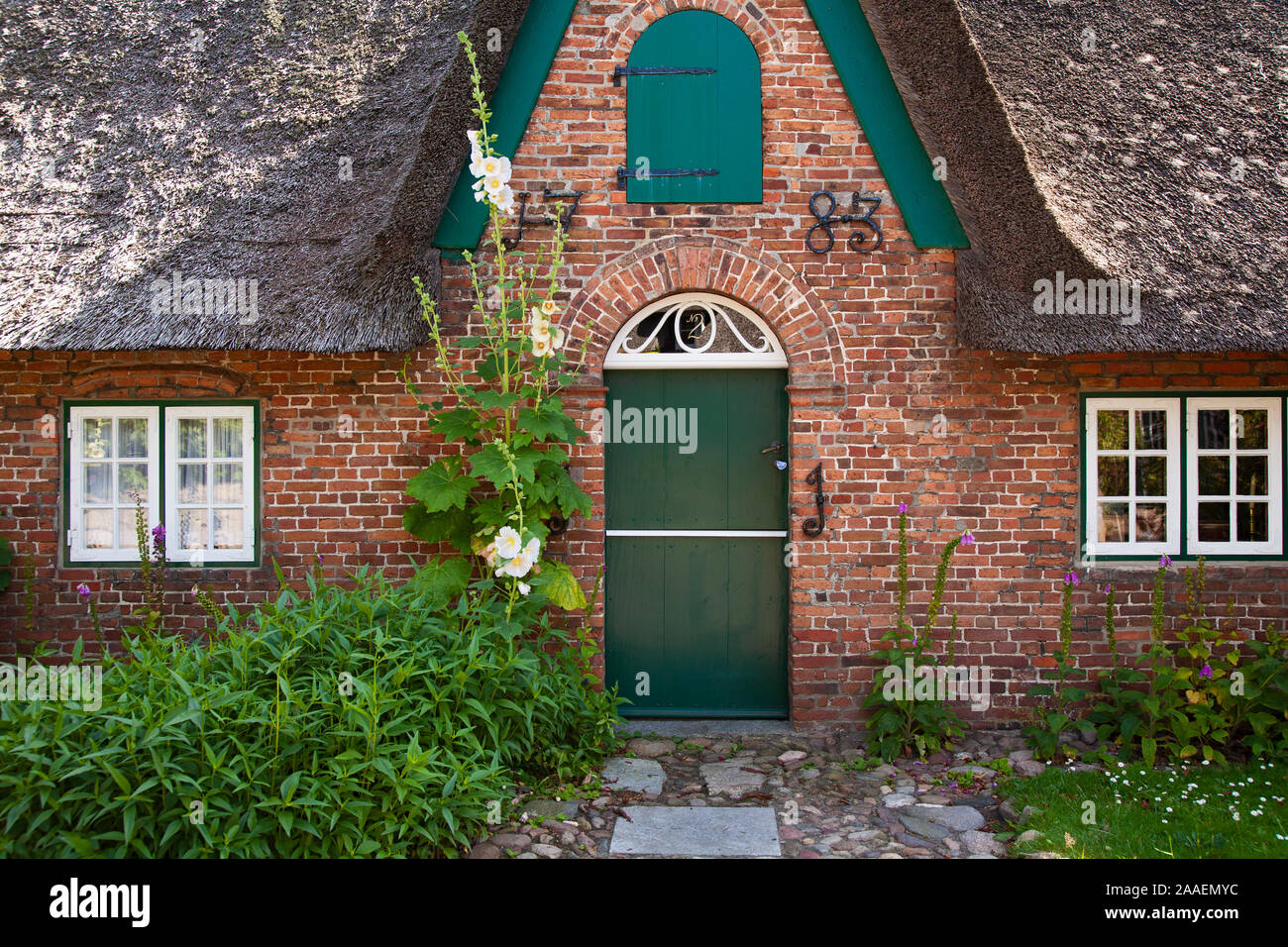 Dettaglio der Fassade des Eingangsbereiches mit Jahreszahl 1783 eines typischen reetgedeckten Friesenhauses mit Stockrosen in Keitum auf Sylt Foto Stock