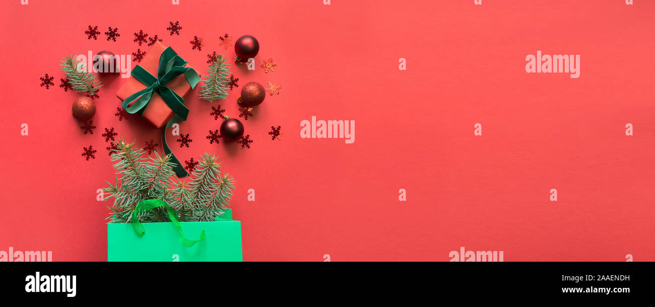 Natale verde sacchetto di carta con dono e vacanze acquisti su sfondo rde. Xmas Shopping concetto. Vista da sopra, piatto laici. Spazio per il testo. Foto Stock