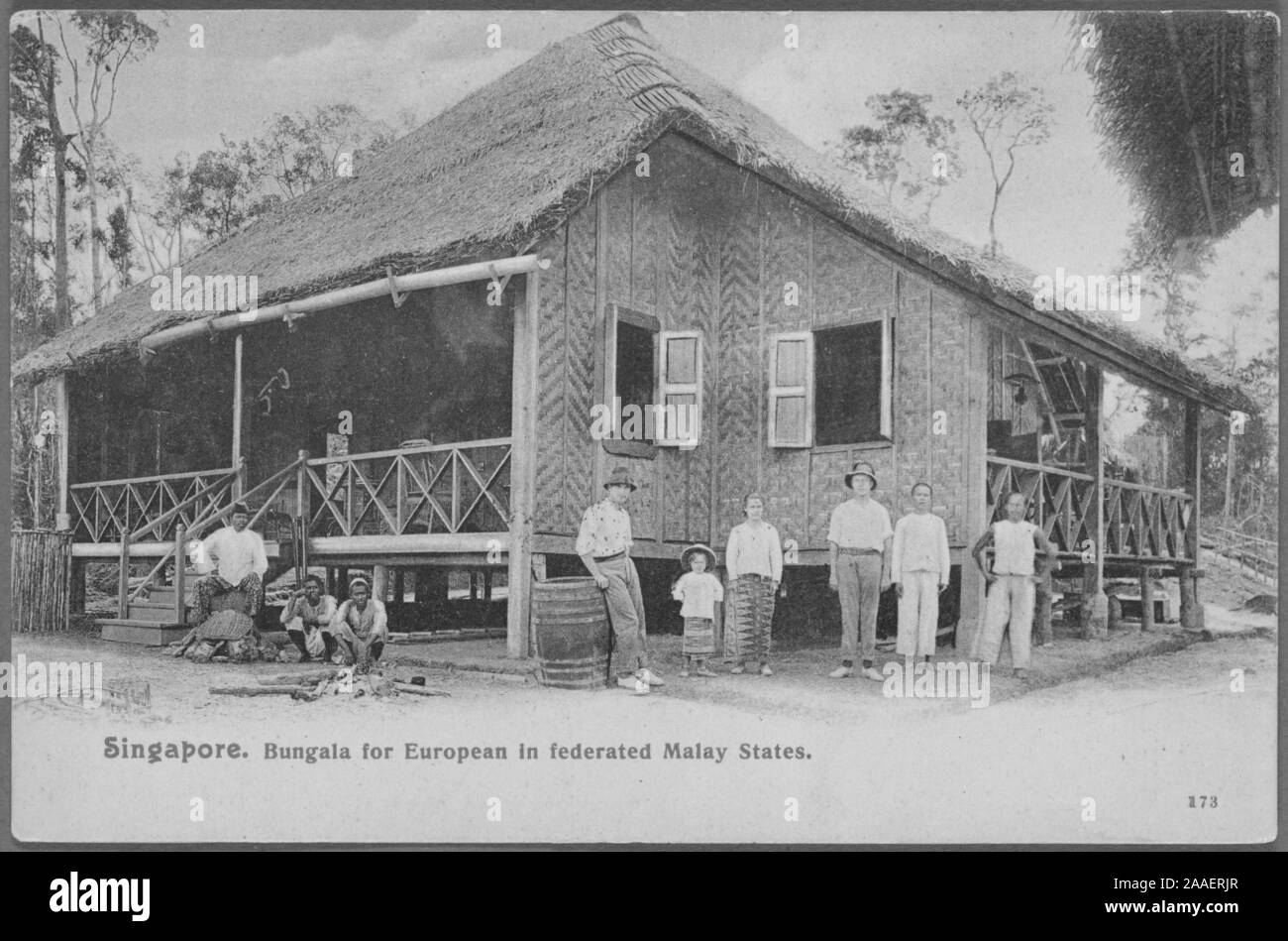 Cartolina inciso da un gruppo di persone in piedi di fronte a un tetto di paglia bungalow, Federated Stati Malay, Penisola Malese, 1908. Dalla Biblioteca Pubblica di New York. () Foto Stock