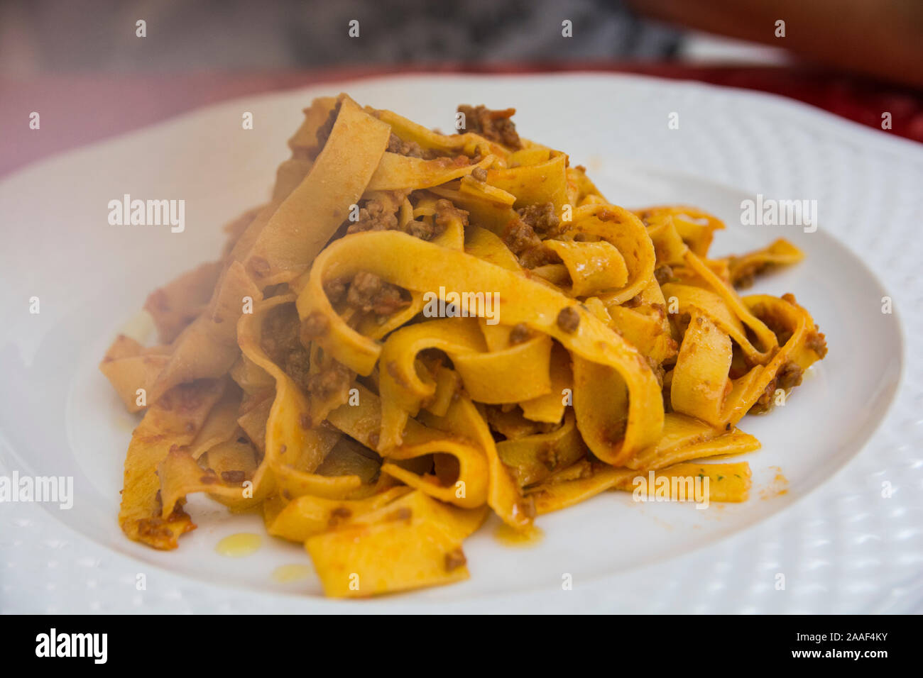 Un steamy tradizionale 'Tagliatelle Ragu', Pasta con carne macinata salsa, servita in una piastra bianca Foto Stock