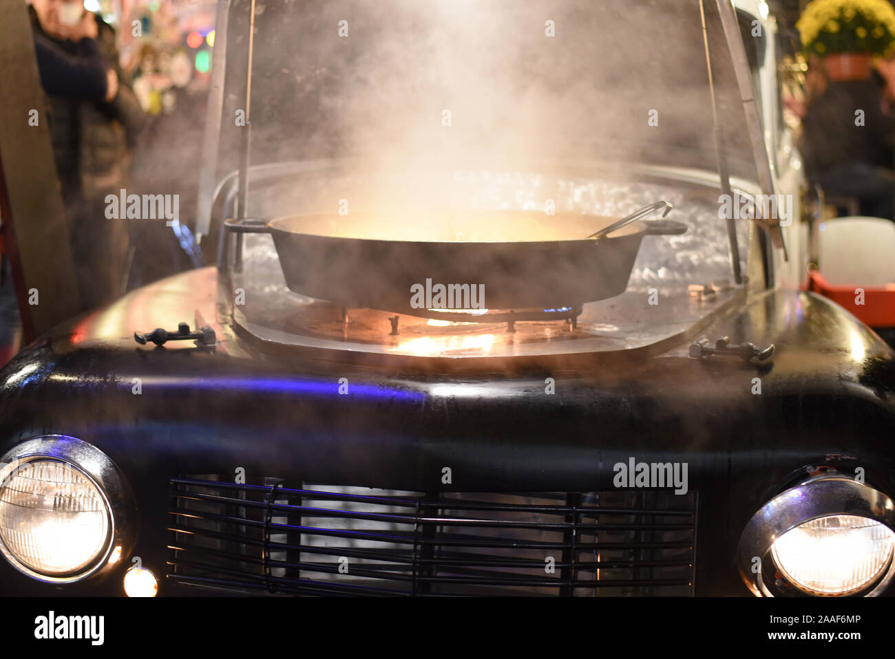 RIGA, Lettonia- Novembre 16, 2019: fornello a gas con una grande padella montato sotto il cofano di una vecchia auto, aprono il fuoco per la cottura del concetto di business locale Foto Stock