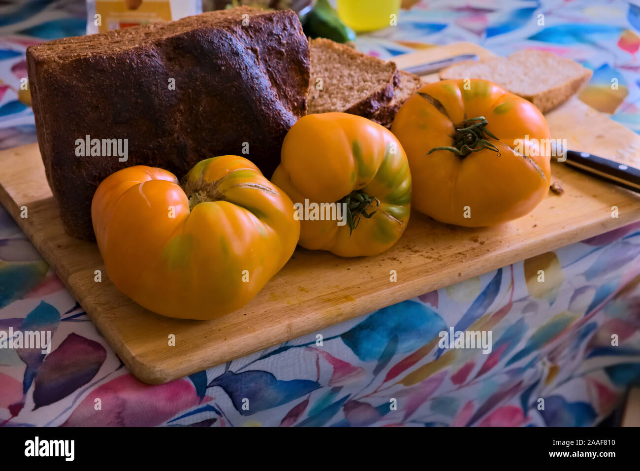 Giallo bistecca di manzo pomodori per il pranzo - Solanum lycopersicum "Coeur de boeuf arancione" con pane di pasta acida Foto Stock