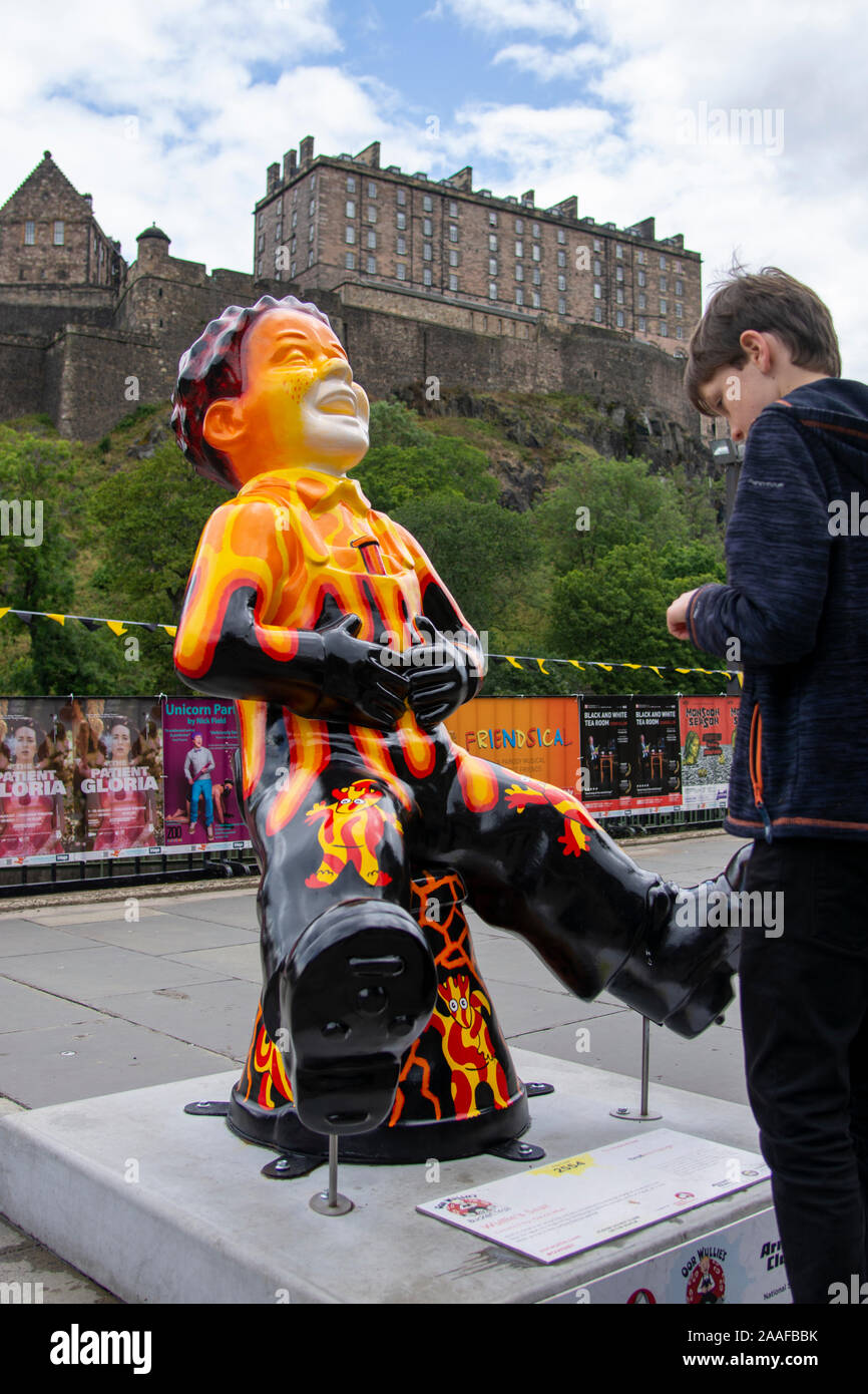 Ragazzo che guarda la statua di Oor Wullie con il castello di Edimburgo sullo sfondo Foto Stock