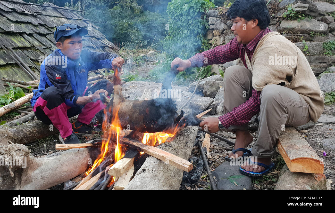 Il nepalese uomini arrostire un capro macellato su un fuoco aperto, regione di Annapurna Himalaya,, Nepal Foto Stock