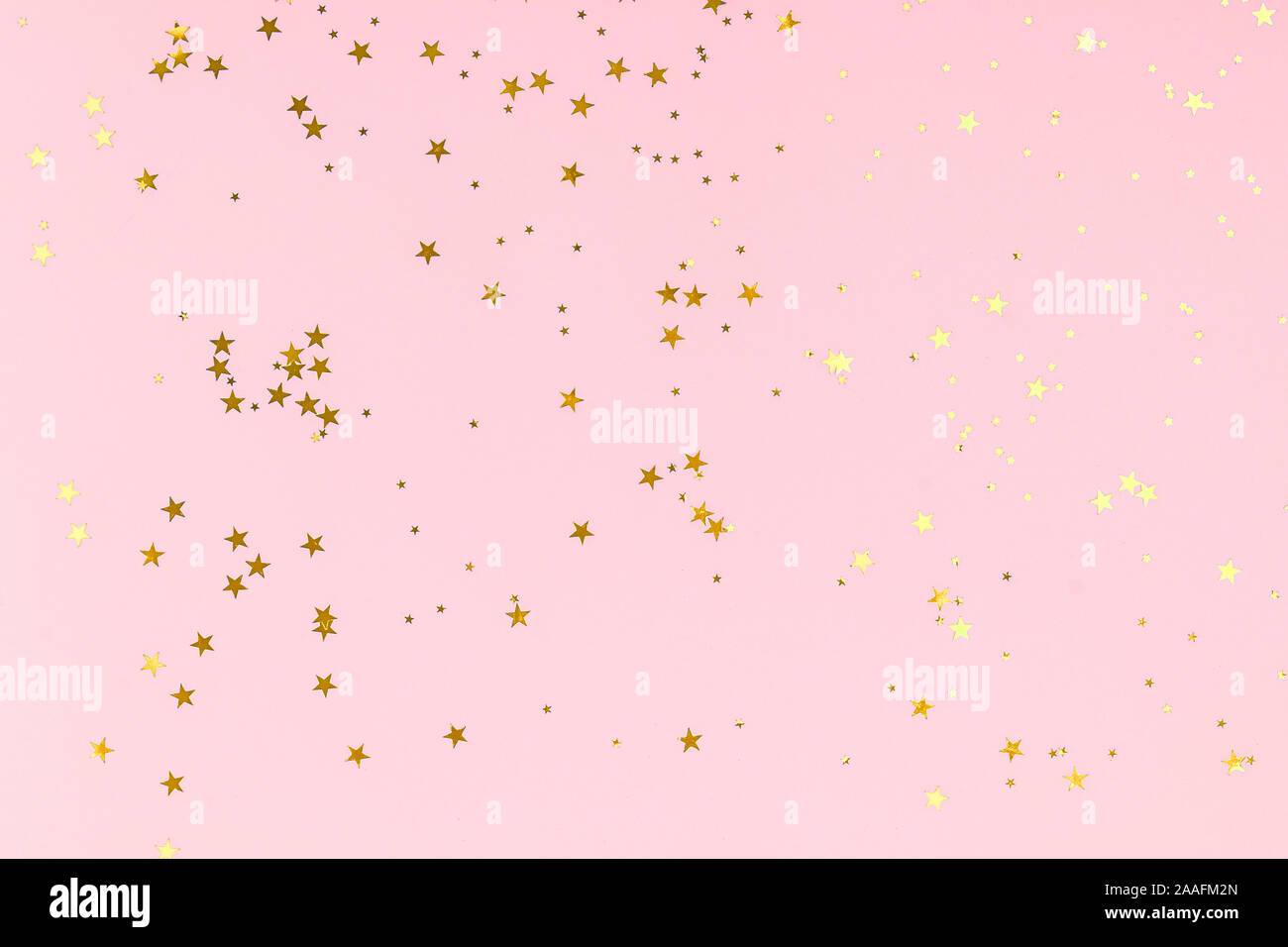 Golden Stars glitter confetti in stile astratto su sfondo rosa. Oro brilla la texture. Holiday anno nuovo sfondo. Anniversario, compleanno. Biglietto di auguri Modello. Foto Stock