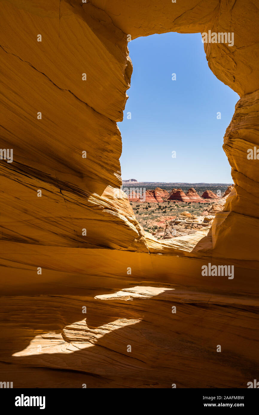 Piccola alcova grotta indossato dalla pietra arenaria con una finestra che si affaccia su diversi shaoed piramide di roccia rossa formazioni hoodoo Foto Stock