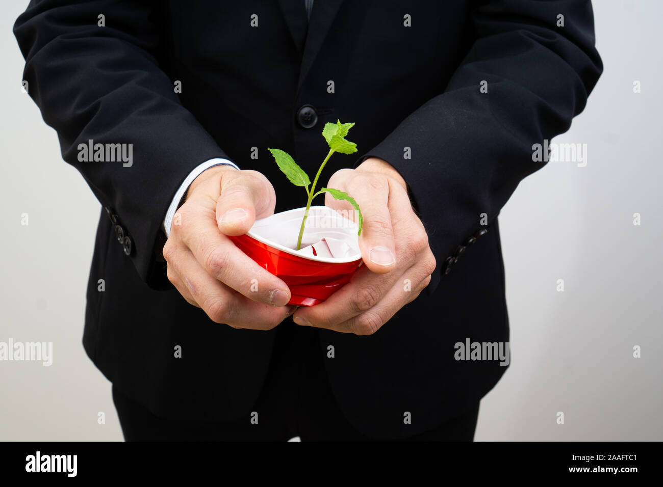 Responsabilità sociale - business man in crash un bicchiere di plastica. evitare di plastica - dire di sì a merci sostenibile per salvare il pianeta. Foto Stock