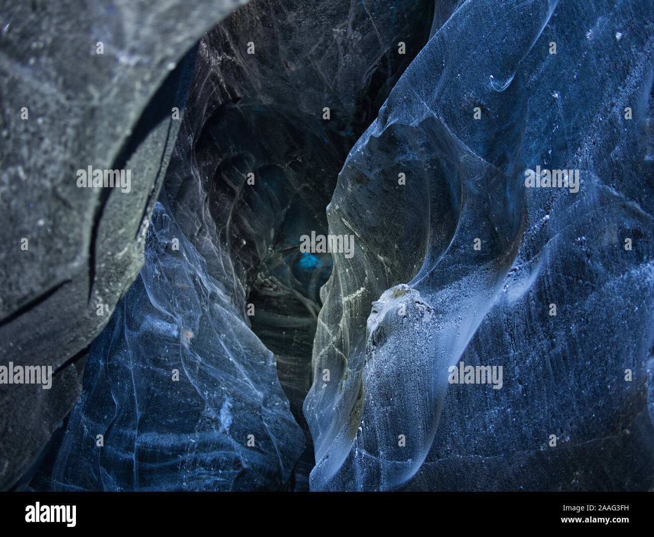 Il ghiaccio illuminato in blu grotta del ghiacciaio in isola Foto Stock