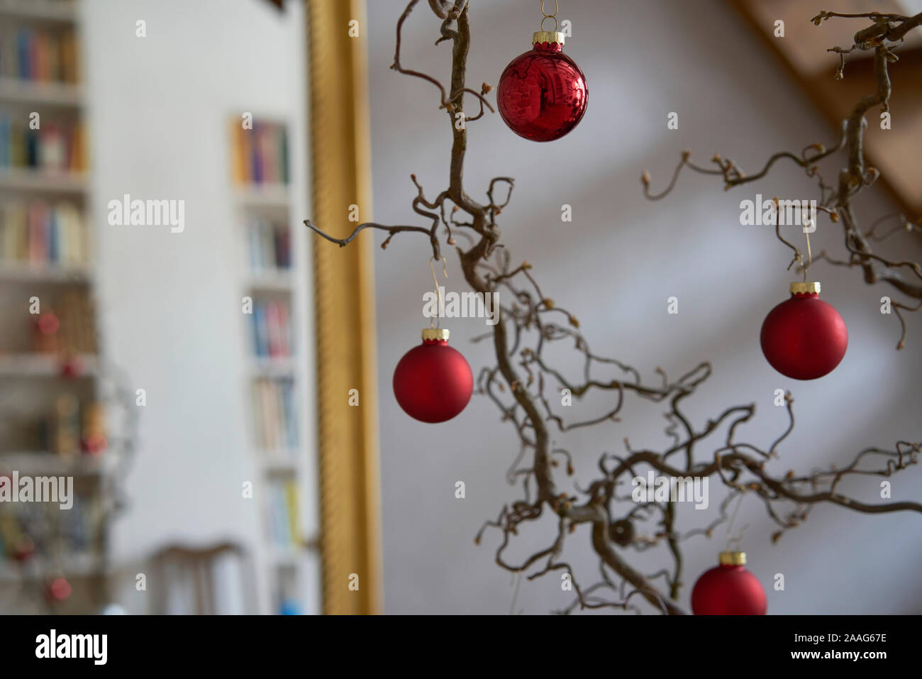 Close up di rosso le palle di Natale presso una filiale di fronte a un muro bianco e specchio con cornice dorata con riflessioni di un appartamento loft Foto Stock