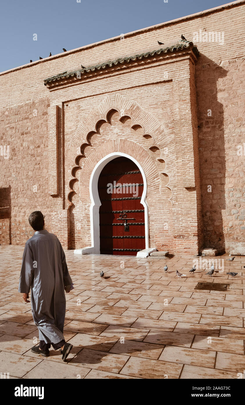 Uomo musulmano che cammina di fronte al legno della moschea di Kutubiyya porta Foto Stock