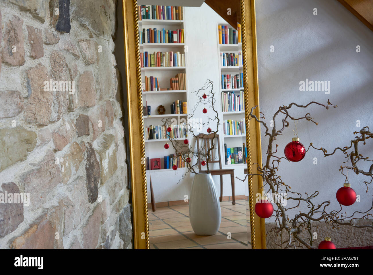 Rosso palle di Natale presso una filiale di fronte a un muro di pietra in un appartamento loft, riflessi in uno specchio con cornice dorata Foto Stock