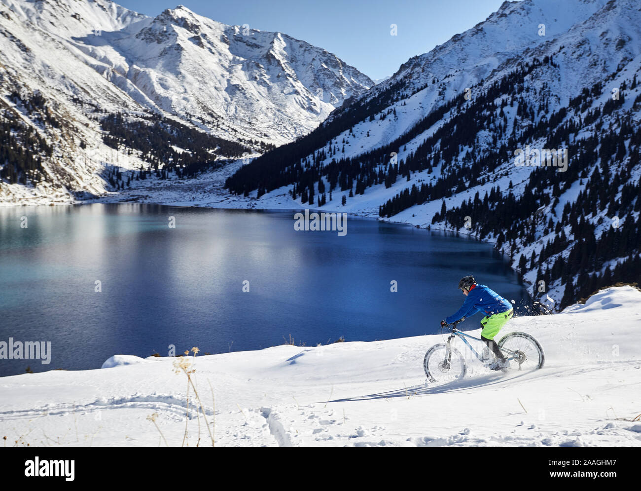Ciclista giostre a neve a riva del lago di montagna ad Almaty in Kazakistan Foto Stock