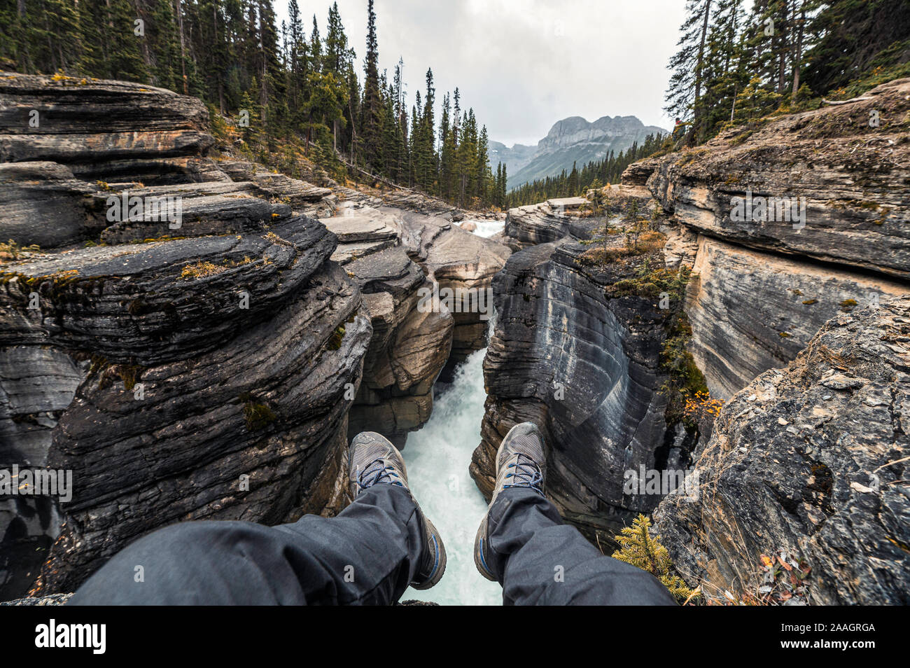 Traveler gambe pendenti su Mistaya Canyon in Icefields Parkway a Alberta, Canada Foto Stock