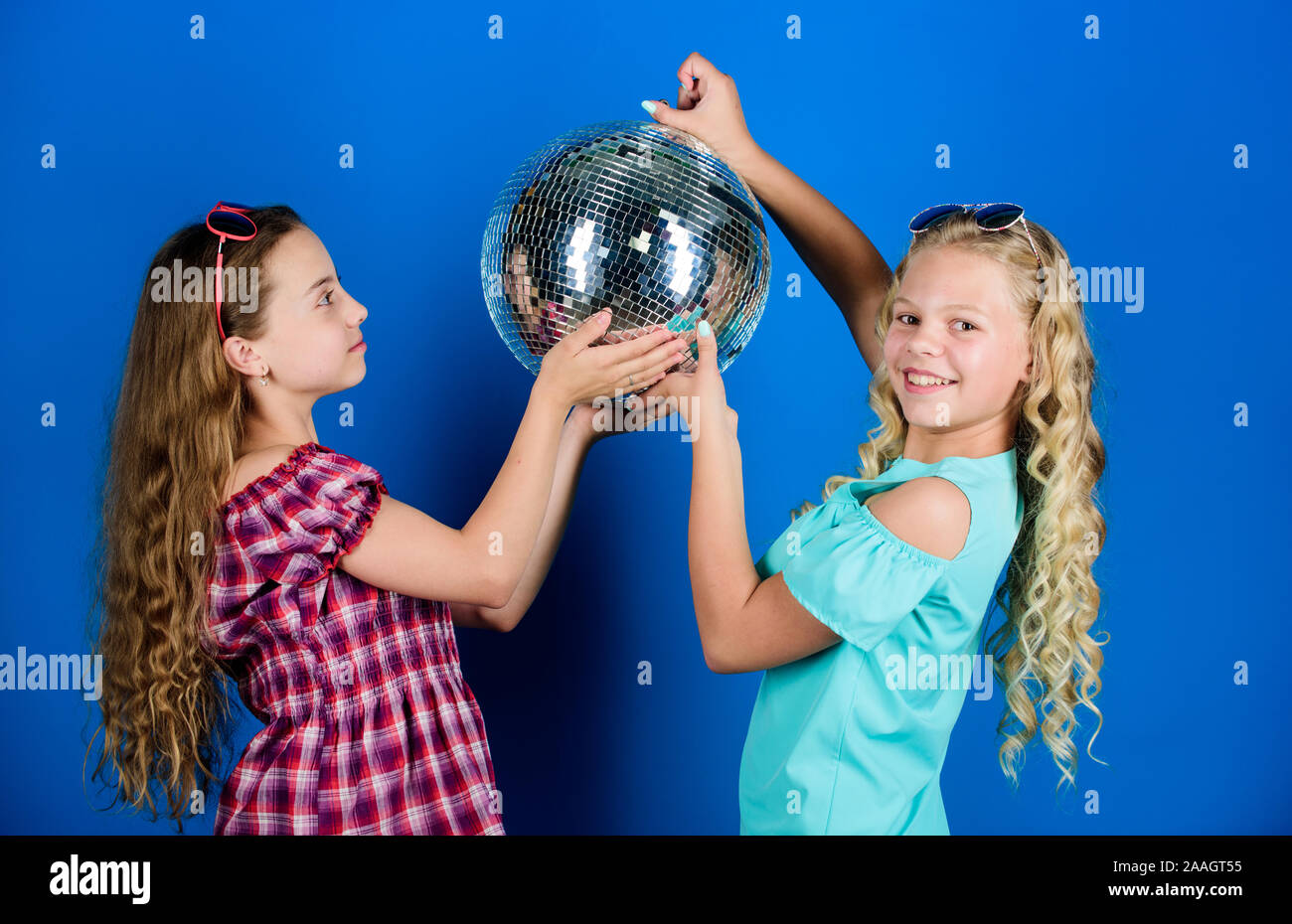 Musica retrò. Gli specchi riflettenti discoteca luci di atmosfera. Holiday celebrazione. Concetto di intrattenimento. Sorelle amici con palla da discoteca. Iniziare a parte. Allegro kids tenere palla da discoteca. Discoteca danze. Foto Stock