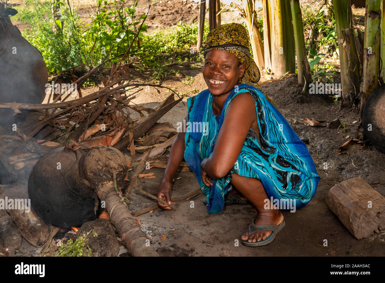 Etiopia, Sud Omo, Jinka, Yenegrew cucire Aari Village, Donna sorridente con home realizzato rendendo ancora araki spirito alcolico Foto Stock
